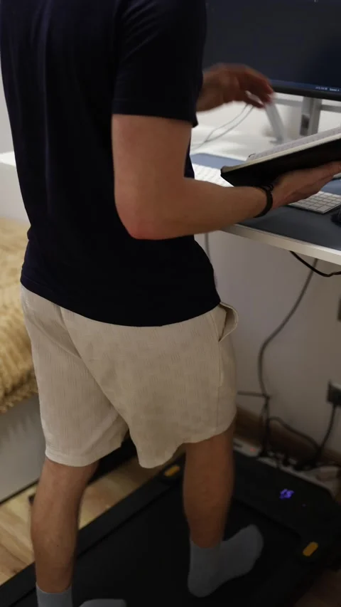 Vertical screen faceless IT student walks on treadmill while reviewing notes and Stock Footage 346881732