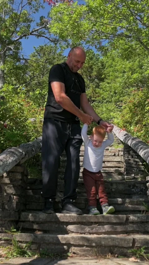 Vertical Screen Father Guides Toddler Down Stone Steps, Holding Hands Under Vidéo 324637652