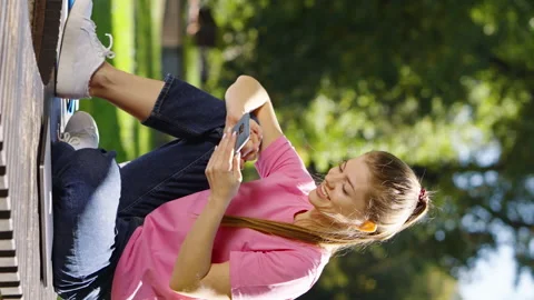 Vertical Screen: Female browsing social media in summer park Stock Footage 223572407