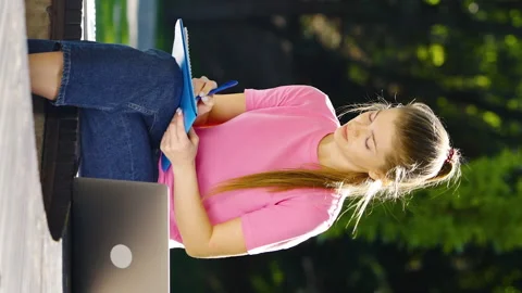 Vertical Screen: Female student studying outside using laptop Stock Footage 223572678