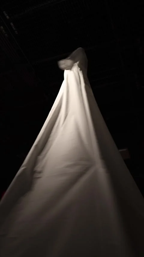 Vertical screen: A flowing white dress suspended in the dark. The fabric drapes  Stock Footage 304459327