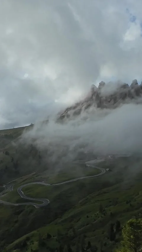 Vertical screen Fog rolling over mountain pass with low clouds hugging jagged Video stock 323979778