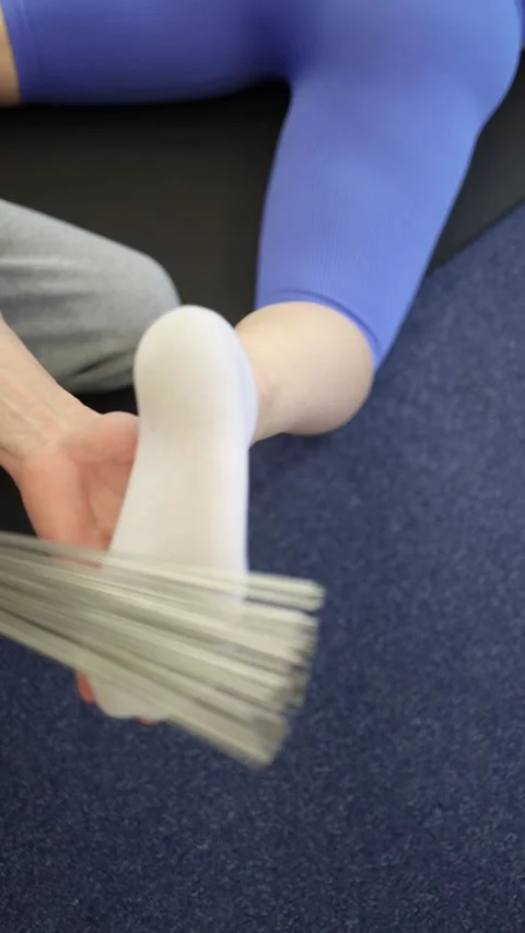 Vertical screen foot massage with fast metal whisk strokes through white sock un Stock Footage 306596730