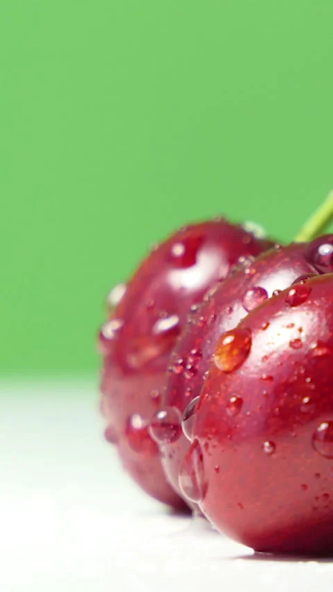 Vertical Screen: Fresh juicy red cherry berry rotate on green background Stock Footage 229798228