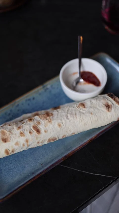 Vertical screen Freshly grilled lavash wrap served on a blue ceramic tray with a Stock Footage 312697091