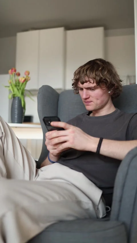 Vertical screen: Frustrated young man holding smartphone, irritated that he can' Stock Footage 302632352