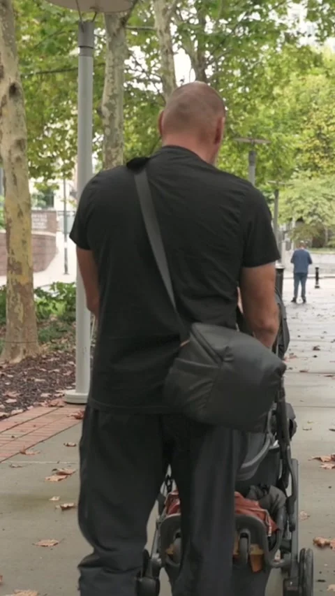 Vertical screen Gentle guardian moving through city streets, Careful father Stock Footage 323093353