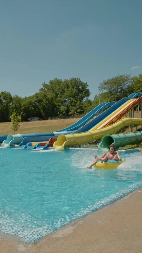 Vertical Screen Girls riding down an orange slide in a water park. Stock Footage 300011547