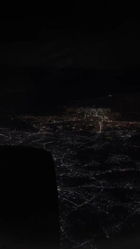 Vertical screen glowing city lights shimmer beneath a night sky viewed from airp Stock Footage 310467455