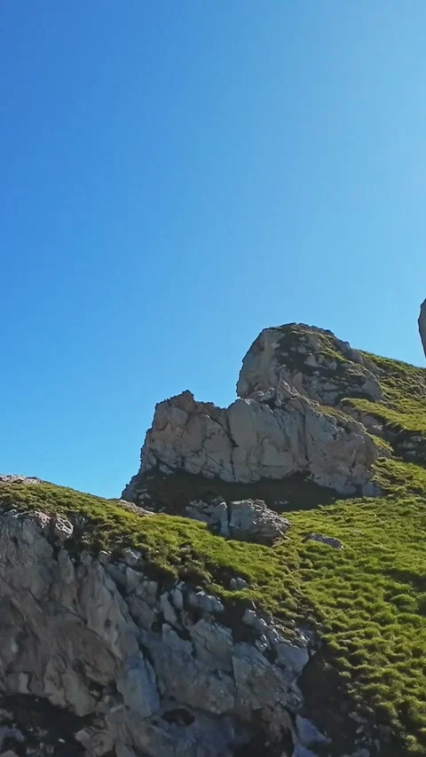 Vertical Screen Green Slope And Rocky Outcrop Under Clear Sky, Sunlit Pasture Vídeo Stock 324637241