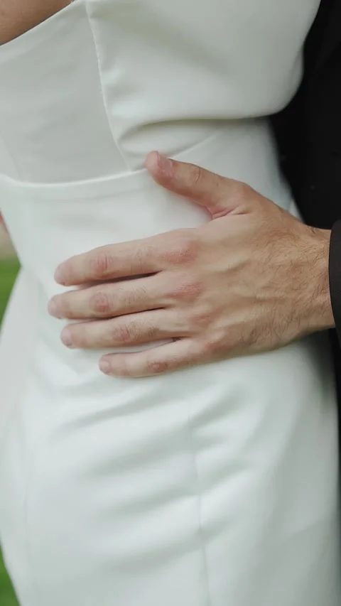 Vertical screen: Groom in suit hugging his bride in white dress celebrating love Stock Footage 308396500