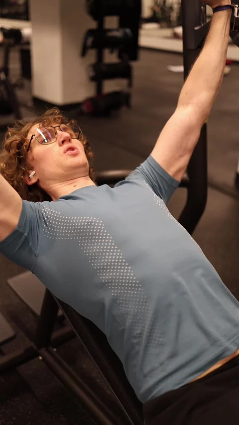 Vertical screen: In the gym, an individual is focused on their bench press worko Stock Footage 301676981