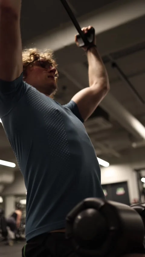 Vertical screen: In the gym, an individual performs a lat pulldown, working on s Stock Footage 301676987