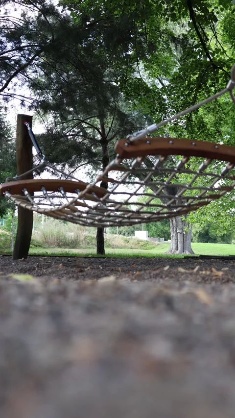 Vertical screen hammock swings gently in the shade of tall trees inviting peace  Stock Footage 315413800