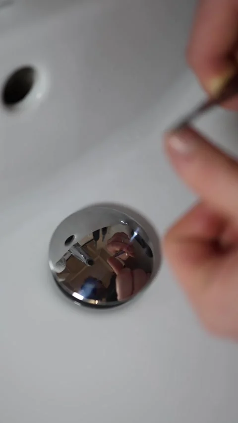 Vertical screen hand holding nail clipper over white sink trimming fingernails w Stock Footage 309330290