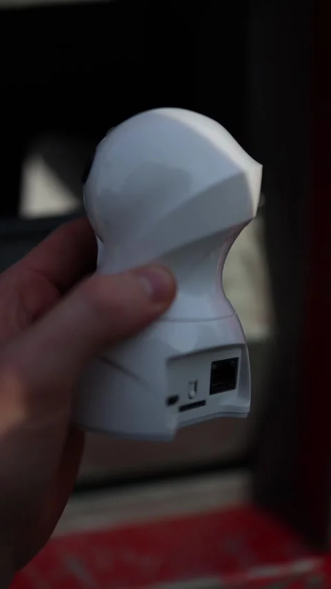 Vertical screen: A hand holding an old white security camera in front of a red t Stock Footage 304884213