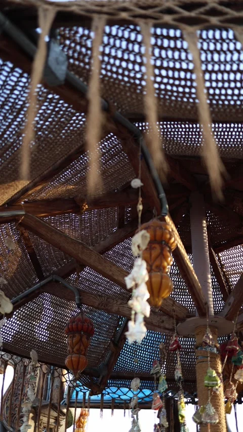 Vertical screen handmade boho lanterns and vintage dolls sway gently under a rus Stock Footage 310521336