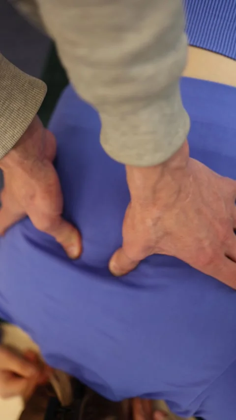 Vertical screen hands apply deep pressure to lower back over tight fabric focuse Stock Footage 306540684