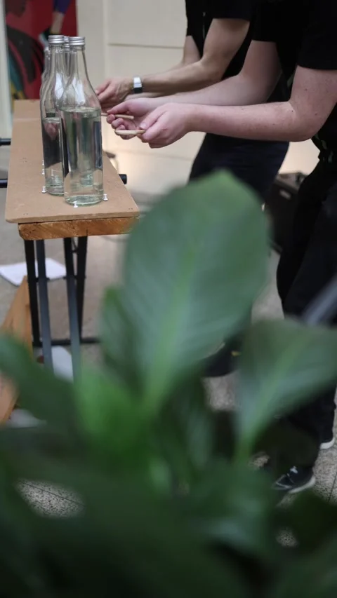 Vertical screen hands play melodies on glass bottles filled with water DIY music Stock Footage 306596764