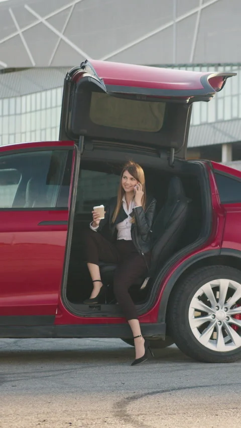 Vertical Screen: Handsome girl sitting in side auto with opened door and talking Stock Footage 274297786