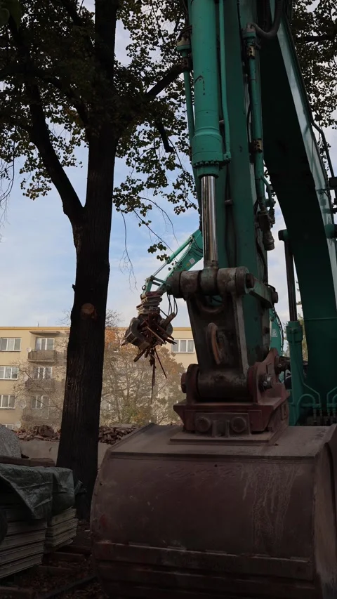 Vertical screen heavy excavator machinery lifts metal debris at an urban demolit Stock Footage 319832522