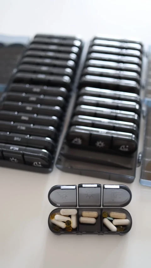 Vertical screen: Here's a well-organized health setup! Rows of pill boxes filled Stock Footage 301240191