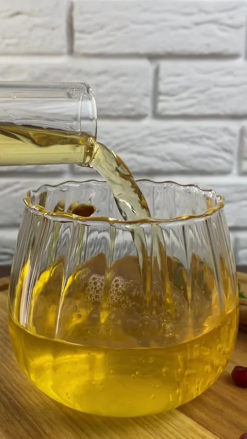 Vertical screen: Hot viburnum tea is poured into a cup from a teapot on a white Stock Footage 265900622