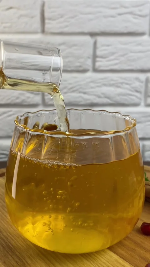 Vertical screen: Hot viburnum tea is poured into a cup from a teapot on a white Stock Footage 265900715