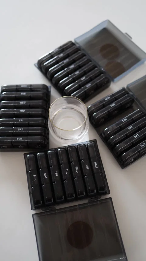 Vertical screen: The image presents multiple compartmentalized pill organizers a Stock Footage 301240162