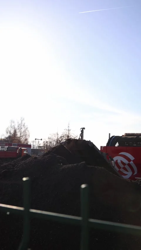 Vertical screen industrial soil loading as a red screening machine moves  Stock Footage 321650803