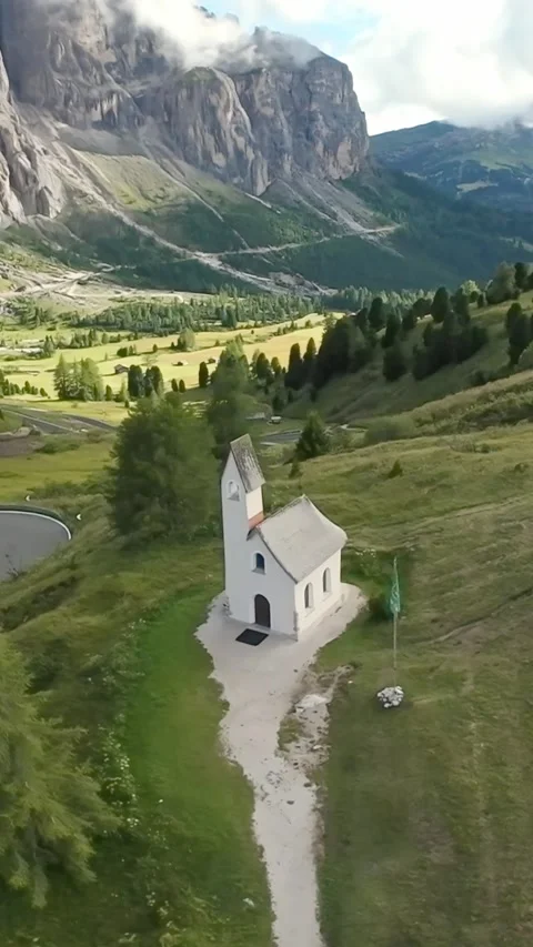Vertical screen isolated chapel beneath towering dolomite cliffs lonely path Vídeo Stock 323242475