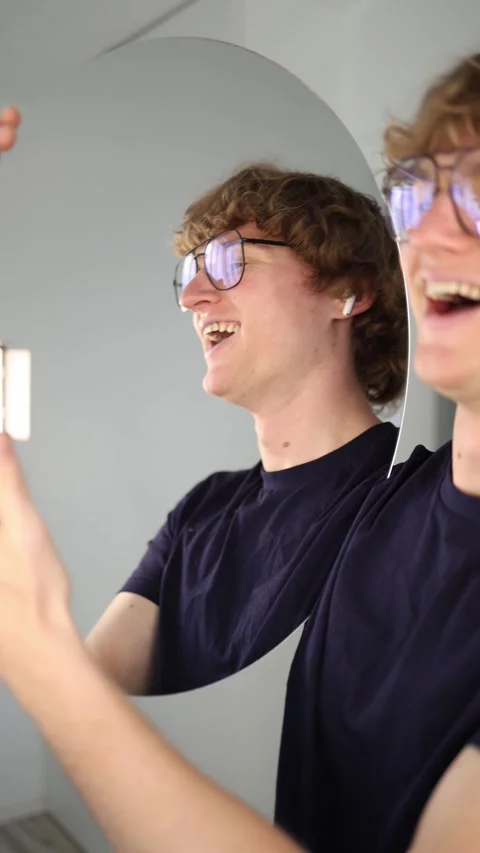 Vertical screen Joyful young man laughs with admiration as he looks into the mir Stock Footage 313268526