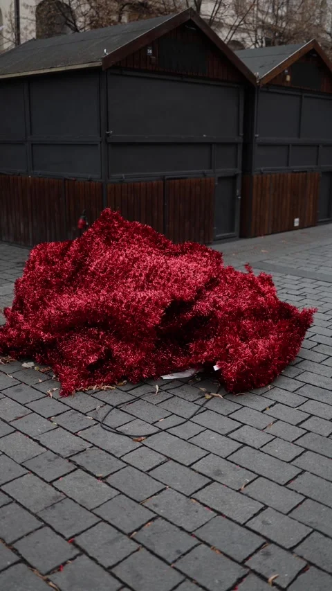 Vertical screen: A large pile of bright red tinsel lying on a cobblestone surfac Stock Footage 297264714