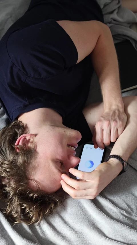 Vertical screen learning with artificial intelligence man lies on bed smiling ne Stock Footage 314979544