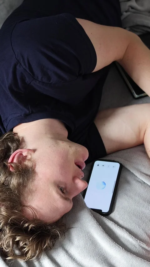 Vertical screen learning with artificial intelligence young man lies on bed hold Vidéo 314979557