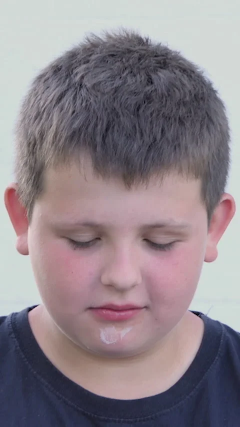Vertical Screen: Little fat boy eats ice cream on the street. Satisfied facial Stock Footage 230042431