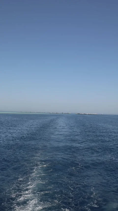 Vertical screen long wake trail cuts through shimmering sea heading toward dista Stock Footage 310518156