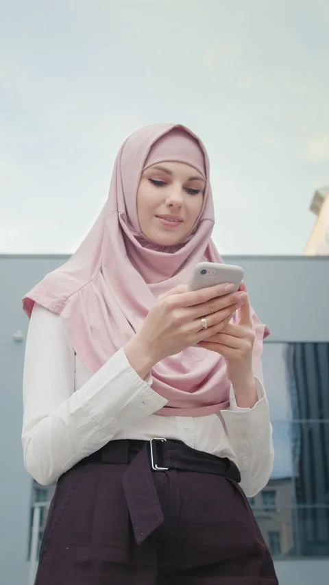 Vertical Screen: Low angle view of beautiful muslim woman standing near modern Stock Footage 272758311