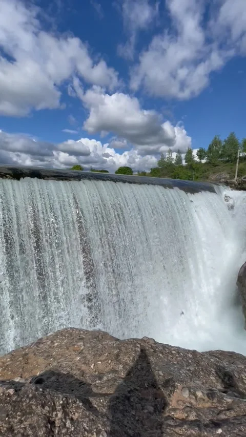 Vertical screen: A majestic waterfall cascading over a rocky edge, surrounded by Stock Footage 296283972