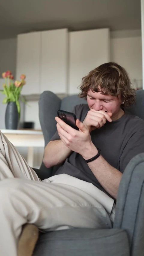 Vertical screen: The man is laughing hard at something funny on his phone, showi Stock Footage 302633124