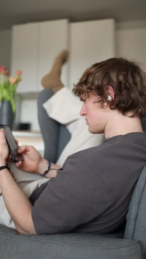 Vertical screen: The man is laying back comfortably, enjoying his time while usi Stock Footage 302633197