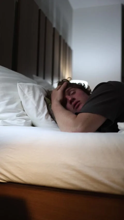 Vertical screen man lies awake in bed overwhelmed with many thoughts in his head Stock Footage 318217599