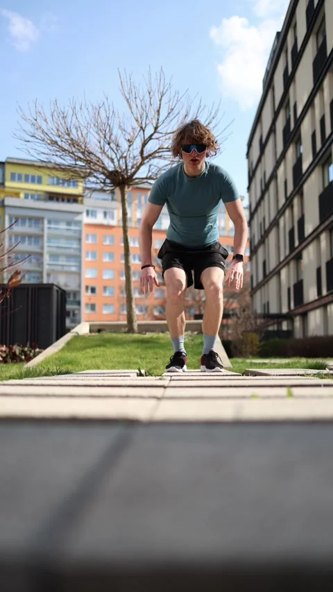 Vertical screen. A man performs explosive squat jumps as a dynamic warm-up in an Video stock 305999107