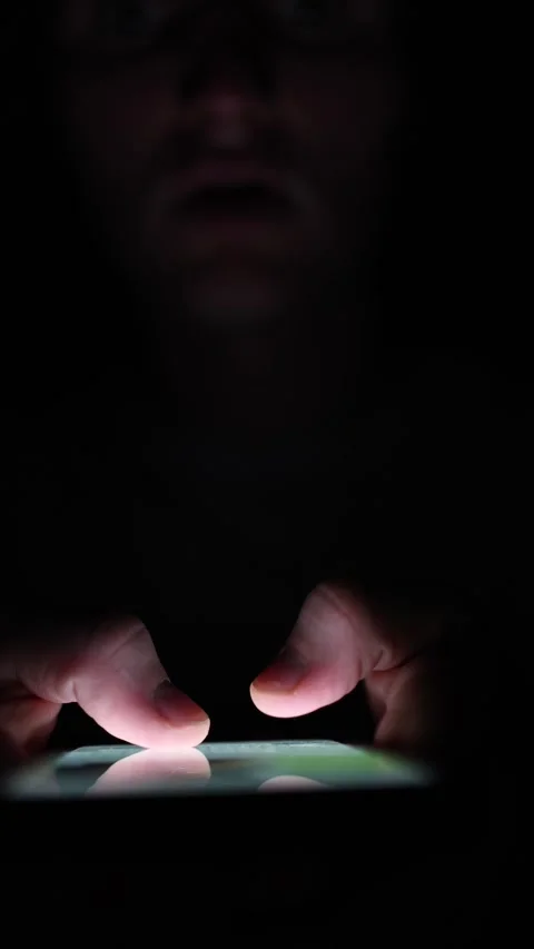 Vertical screen Man quietly types on phone in the dark his glowing fingers tappi Stock Footage 313842811