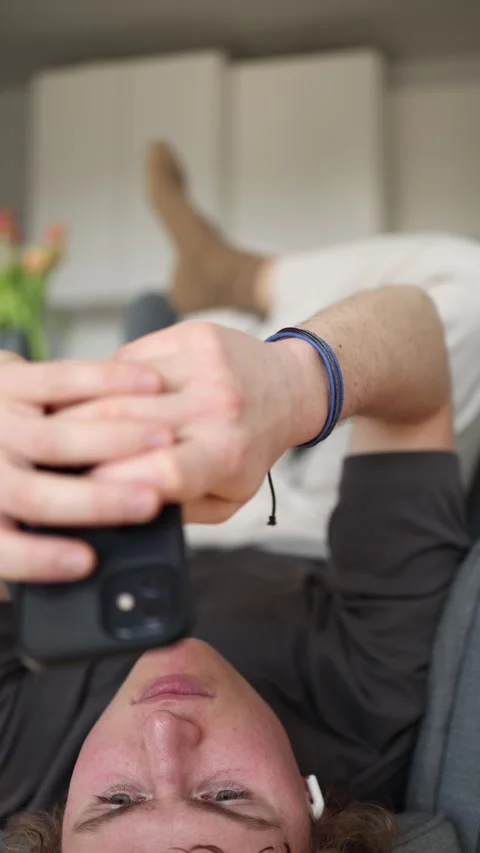 Vertical screen: The man is relaxing on the couch, enjoying some quality time on Stock Footage 302633210