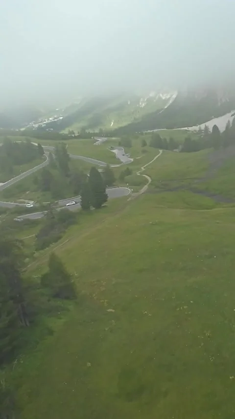 Vertical screen Mistcovered valley with lush greenery, Path weaving amid foggy Stockbeeldmateriaal 323242338