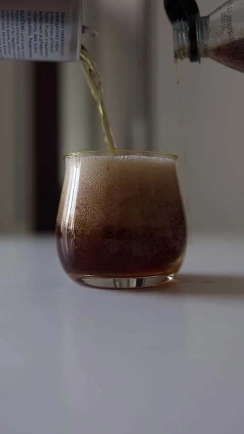 Vertical screen mixing soda and energy drink two different beverages poured into Stock Footage 312175406