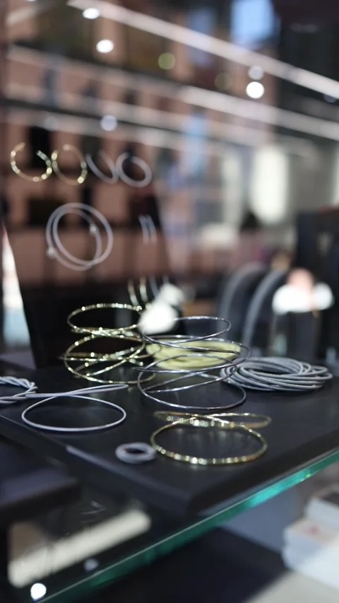 Vertical screen: A modern jewelry display featuring delicate metallic rings and  Stock Footage 304459544