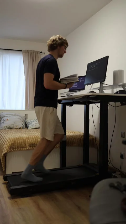 Vertical screen motivated student studies coding while running on treadmill and  Stock Footage 346881517