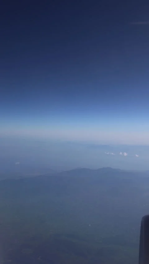 Vertical screen mountain landscape from airplane window with dreamy blue haze st Stock Footage 310471115